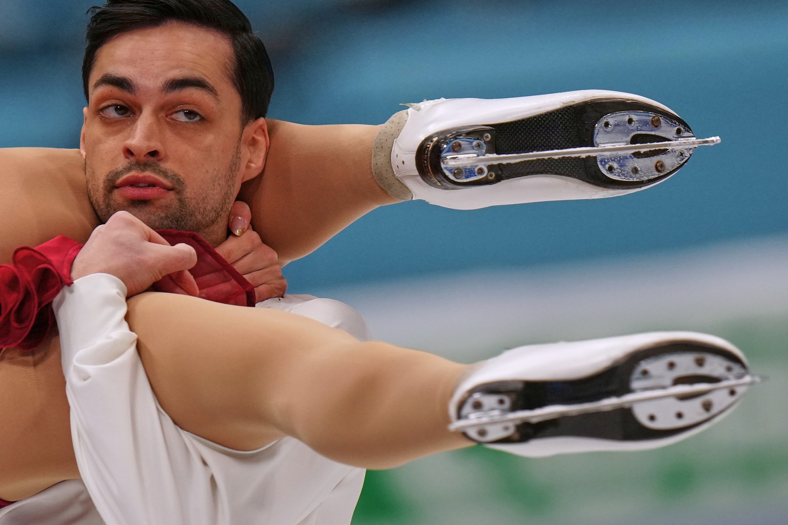 A pair of ice dancers perform, one holding the other up by their legs.
