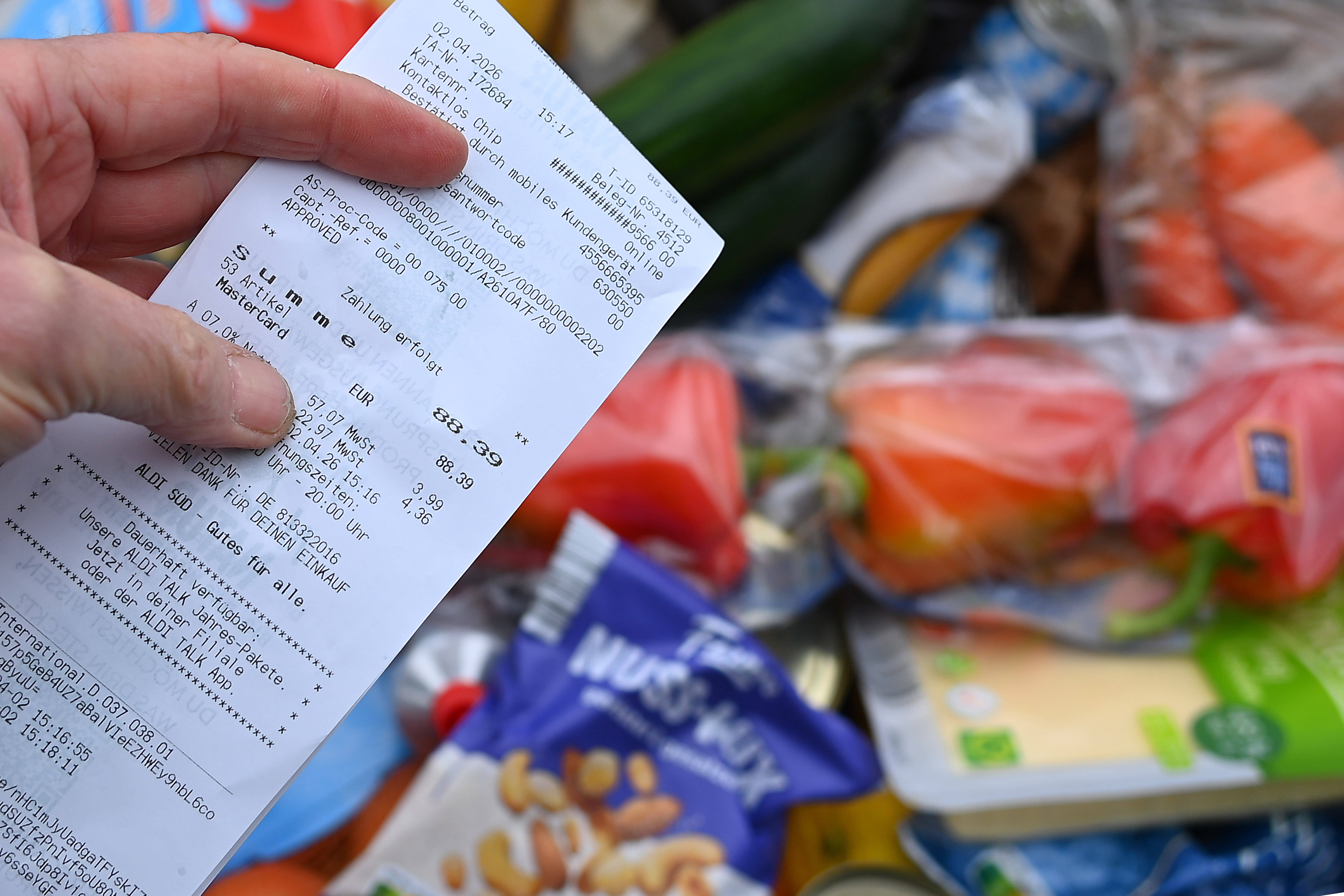 A person holds up a receipt, above a pile of groceries.