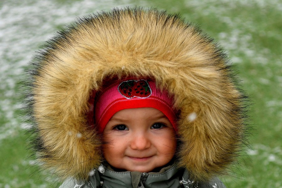 A portrait of a young girl wearing a very fuzzy fur-lined hood.