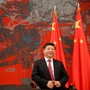 Chinese President Xi Jinping  sits in a chair in front of two Chinese flags.