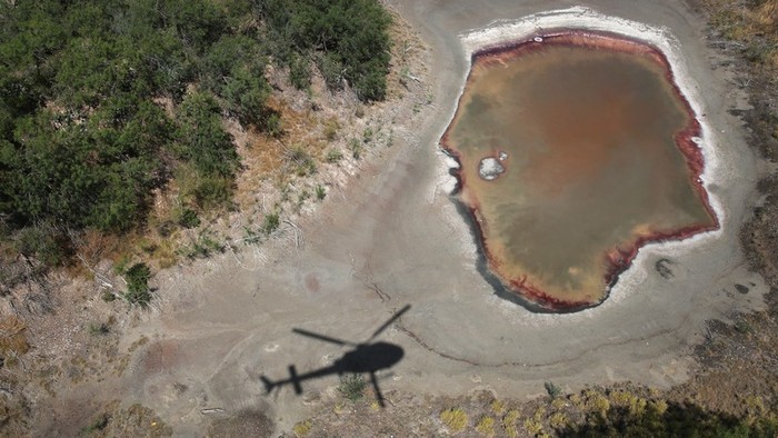 An air interdiction helicopter from U.S. Customs and Border Protection flies past a drought-stricken pond by the U.S.-Mexico border