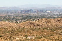 Phoenix, Arizona, from South Mountain Park on June 18, 2020. There are brown hills in the foreground, and the city's skyline in the background.