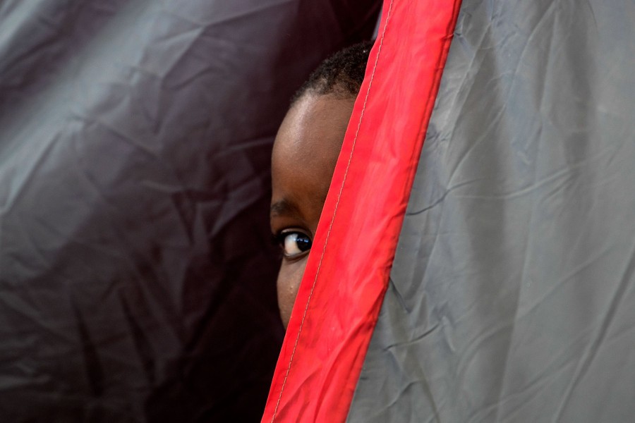 A child peeks out from inside a tent.