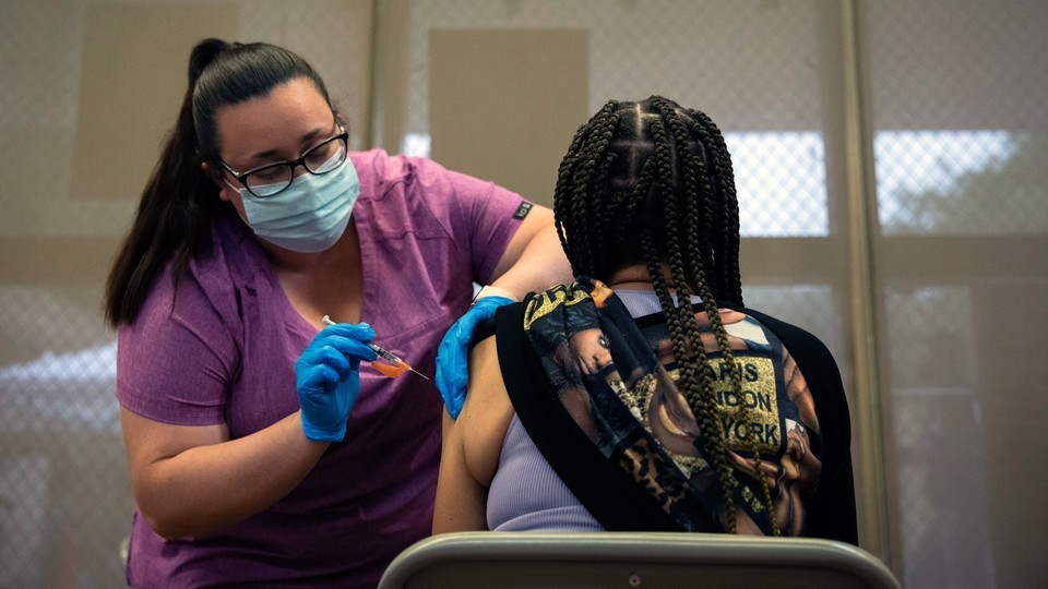 a health worker administers a vaccine to a person sitting in a chair