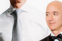 Jeff Bezos stands in front of a poster of himself