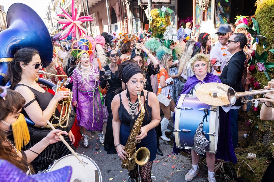 People in costume on a street watch performers playing instruments.
