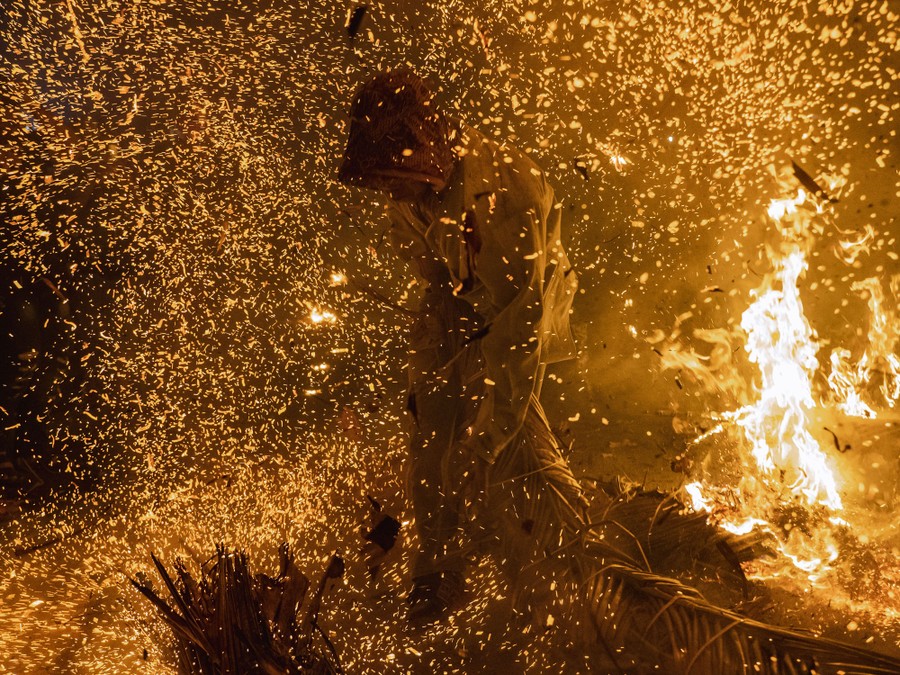 A person stands amid a cloud of burning embers.