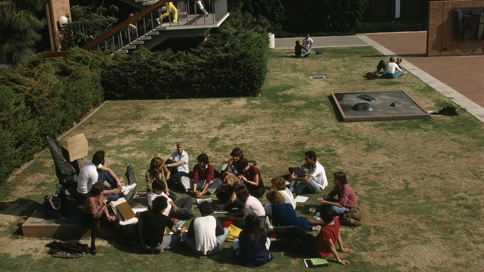 College students sitting on a grassy field.