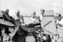 Young American soldiers in the South Pacific stand behind an anti-aircraft gun while eating ice cream, 1943