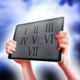 Against a stormy sky, hands hold up an iPad tablet with Roman numerals engraved on it.