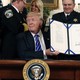 President Trump holds a signed bill in at the White House.