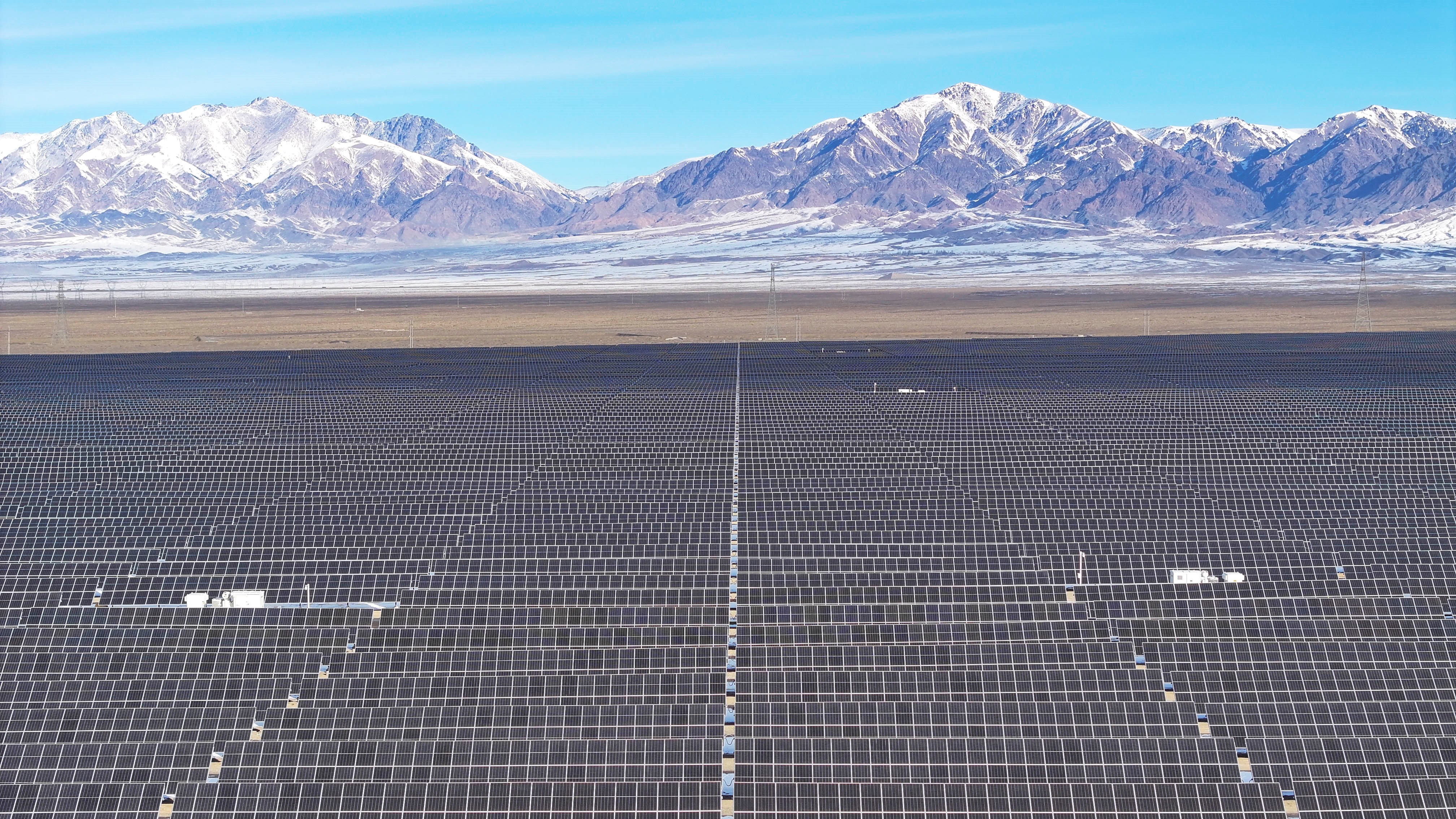 Vast grids of solar panels, backdropped by snow-covered mountains.
