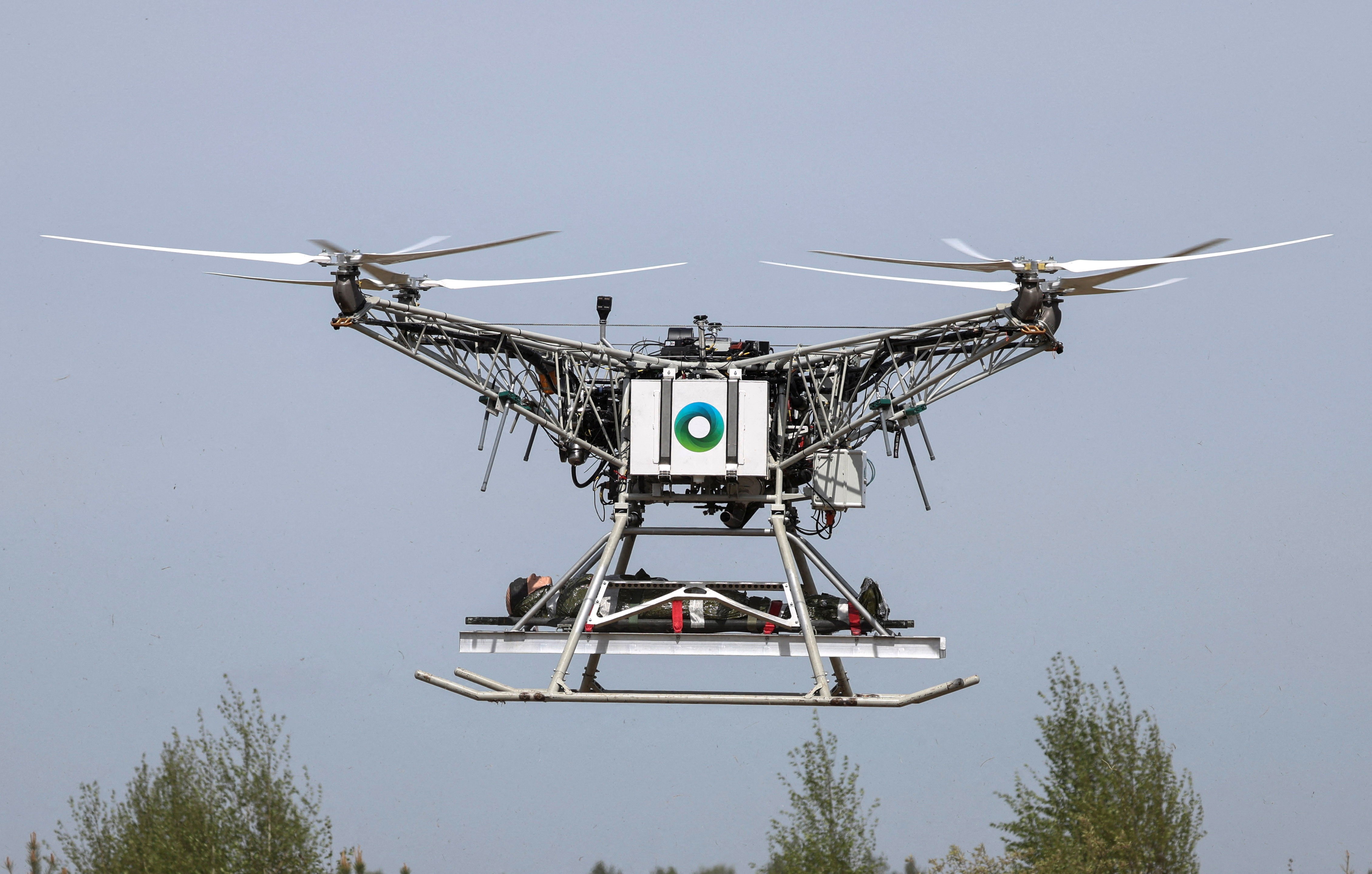 A large four-rotor unmanned aerial vehicle carries a dummy in a test to evacuate wounded soldiers.