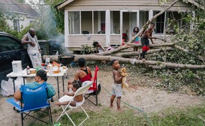 A famile prepares dinner in their front yard after Hurricane Ida.