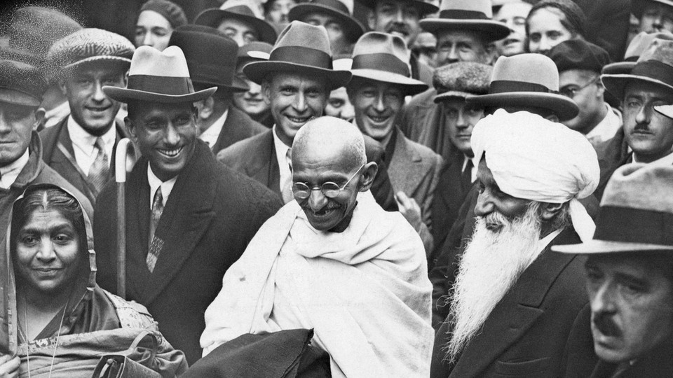 A black and white photograph of Gandhi in a crowd