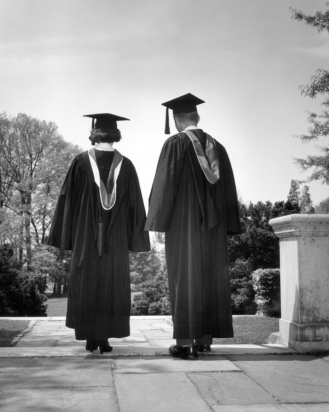 Two graduates walking in caps and gowns
