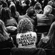 Black-and-white photo taken in a seated crowd at Robert F. Kennedy Jr.'s confirmation hearing, where a woman wears a "Make America Healthy Again" T-shirt.
