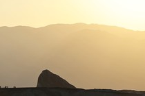 A Death Valley outcropping in front of a mountain, in hazy yellow heat