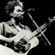 A black-and-white photo of Tracy Chapman playing the guitar and singing.