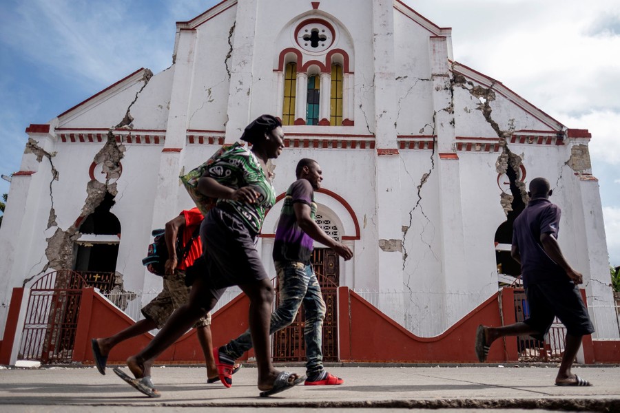 Several people run past a heavily damaged church.