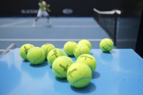 Eleven tennis balls near a tennis court