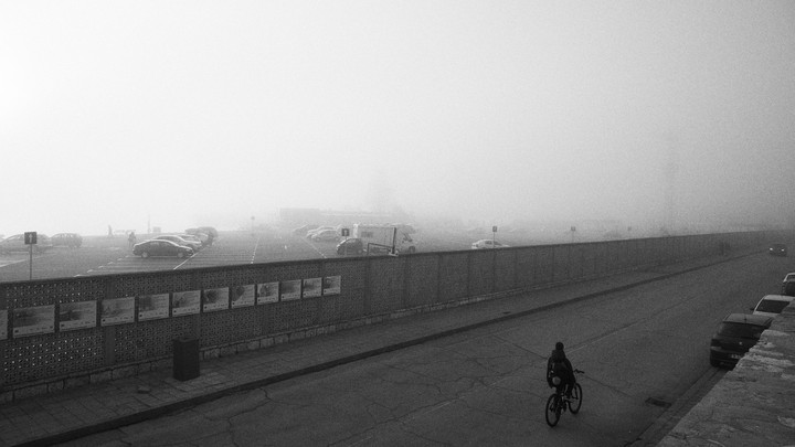 A person rides a bike near a parking lot