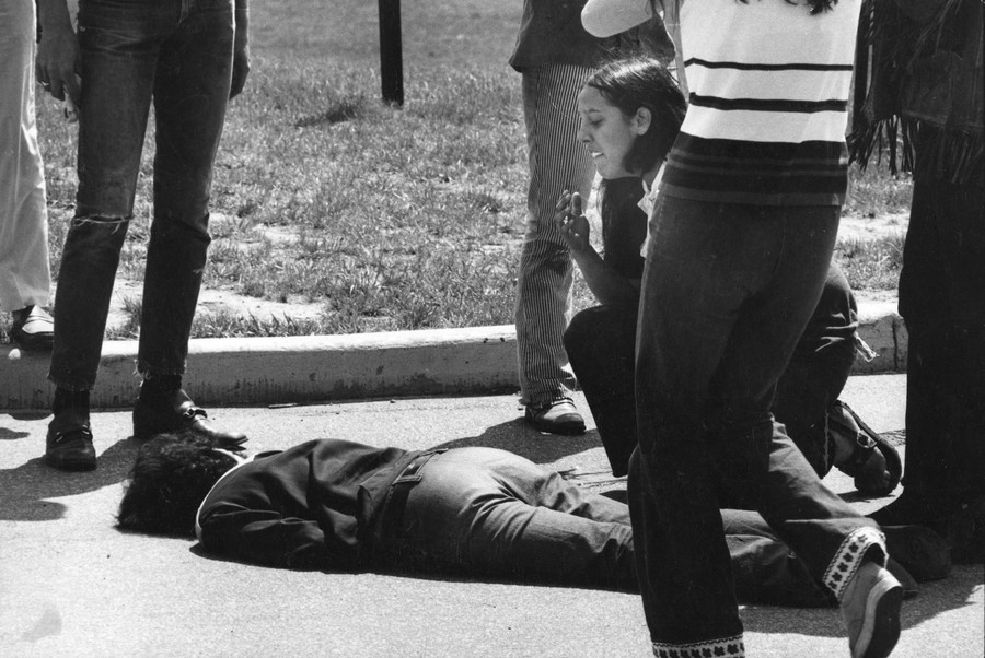Several people stand nearby as a young woman kneels beside the body of a demonstrator who has been shot.