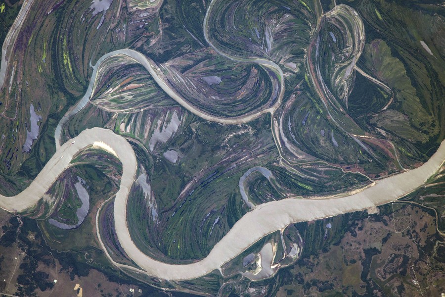 An aerial view of twisted and braided land, formed over many years by a meandering river