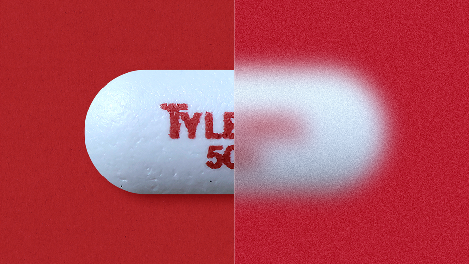 A close-up of a Tylenol pill against a red background. Half the photo is blurred and half is in focus.