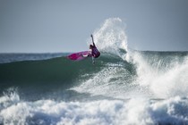 a photo of surfer in pink at the crest of a wave