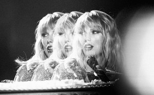 A stylized, black-and-white photo of Taylor Swift singing into a microphone