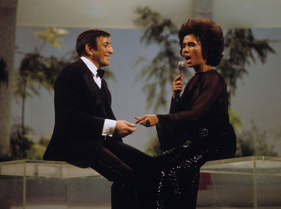 Tony Bennett and Lena Horne sing together, seated, in a television studio.