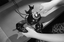 A woman's hand dials an antique phone.