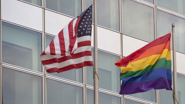 An American flag and a rainbow pride flag are pictured next to each other.
