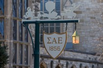 A sign on a lamppost with the initials of Sigma Alpha Epsilon on it 