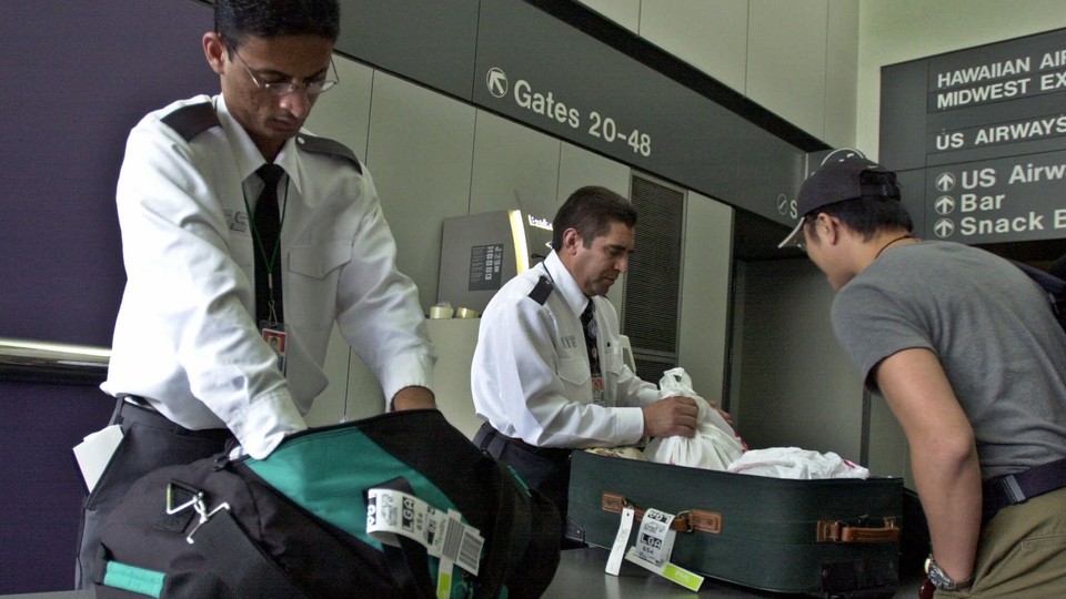 San Francisco International Airport security personnel search through a passenger’s luggage.