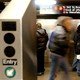 People standing on a subway platform in New York City, framed by two turnstiles