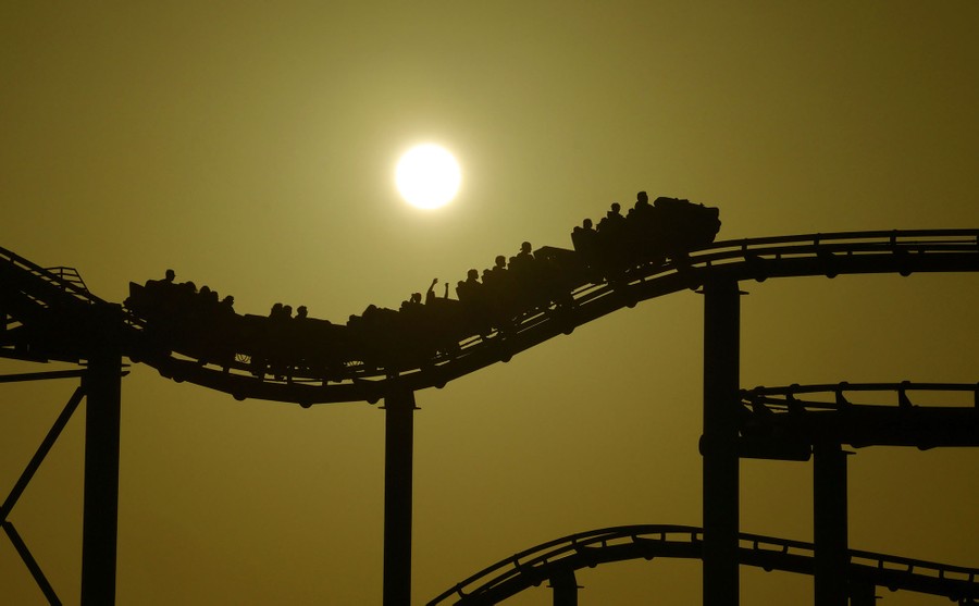 The sun sets behind a roller coaster.
