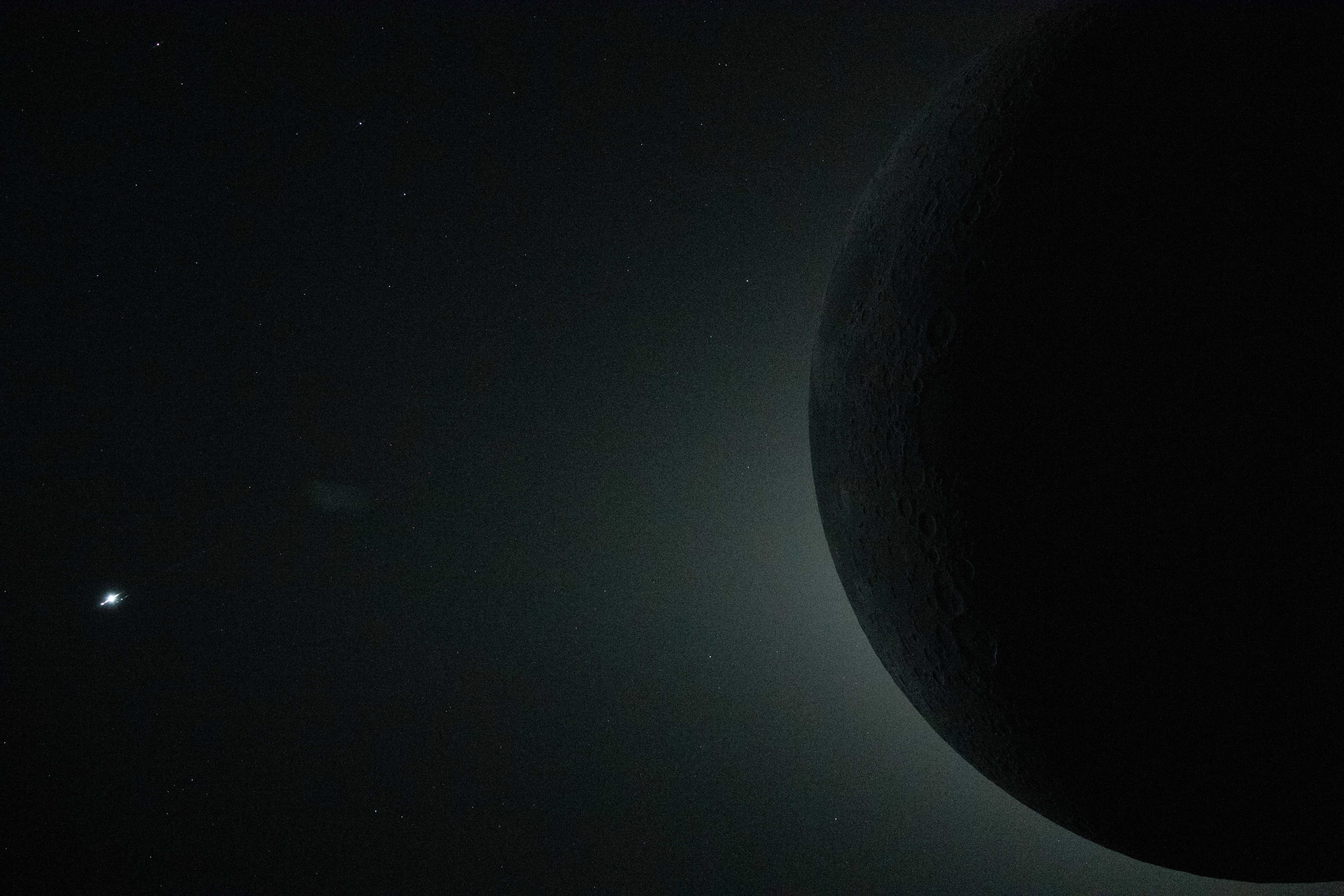 A close-up view of the moon, seen from the Orion spacecraft, during an eclipse, silhouetted against the glowing corona of the sun