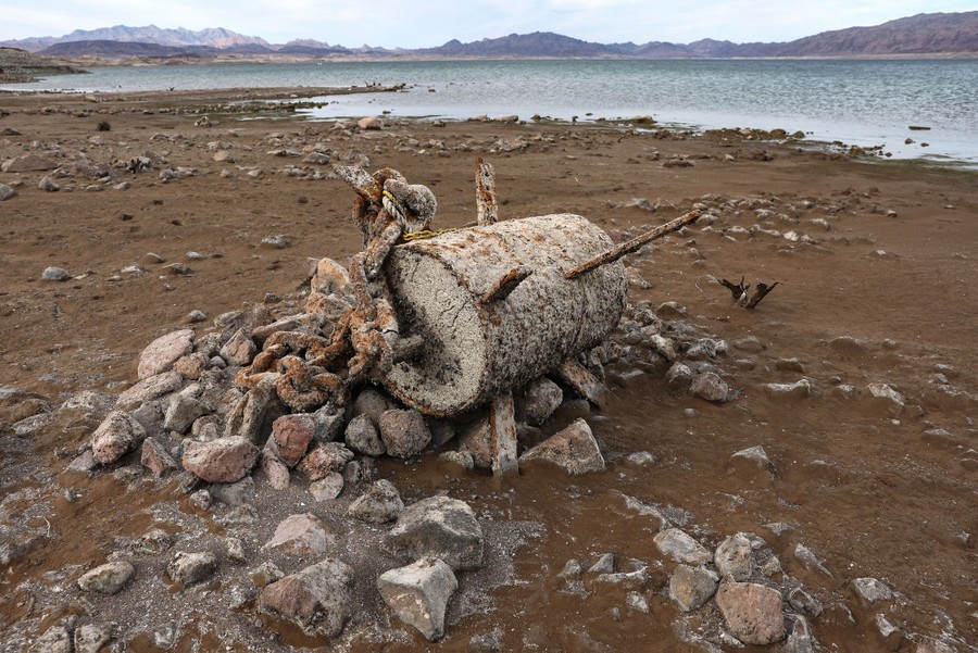 A cylindrical hunk of rusted debris sits on dry ground near Lake Mead.