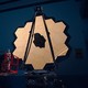 A photograph of the James Webb Space Telescope's primary mirror—an array of hexagonal, gold-covered tiles—illuminated in a dark room