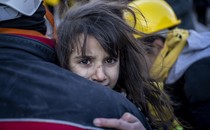 A child is carried by rescue workers.