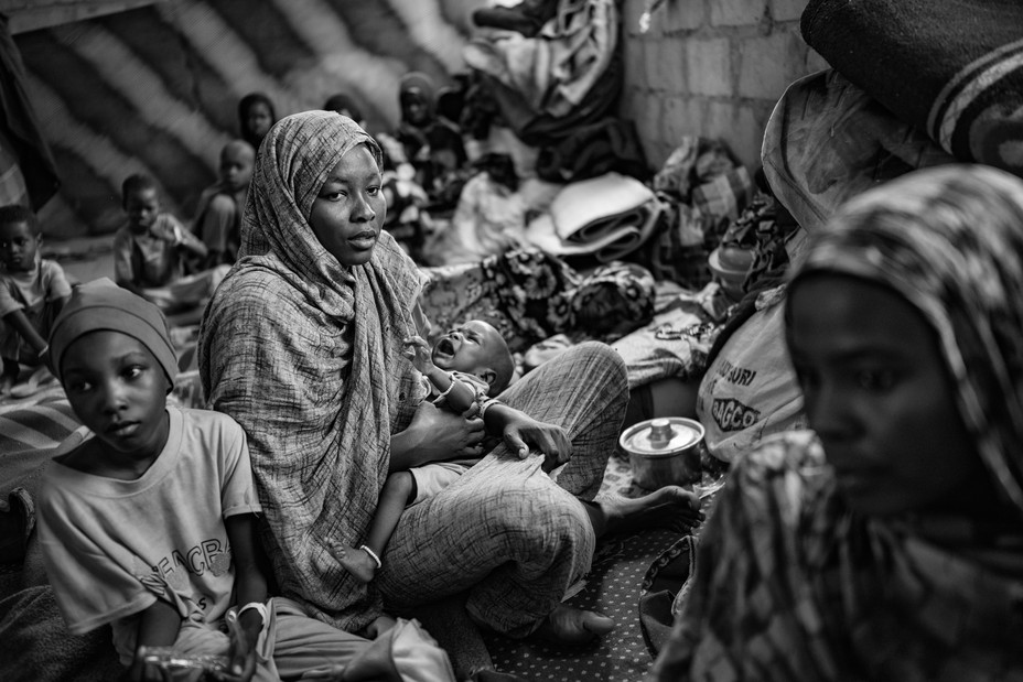 Picture of Taysir Ibrahim Juma, 30, holding her two-month-old son, Mujahid, as she sits among relatives and other Sudanese refugees. 