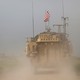 A man gestures at U.S. military vehicles driving in the town of Darbasiya in Syria.
