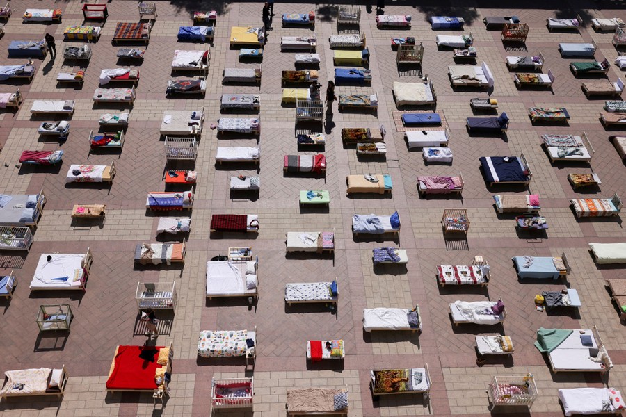An elevated view of dozens of beds and cribs arranged on a public square
