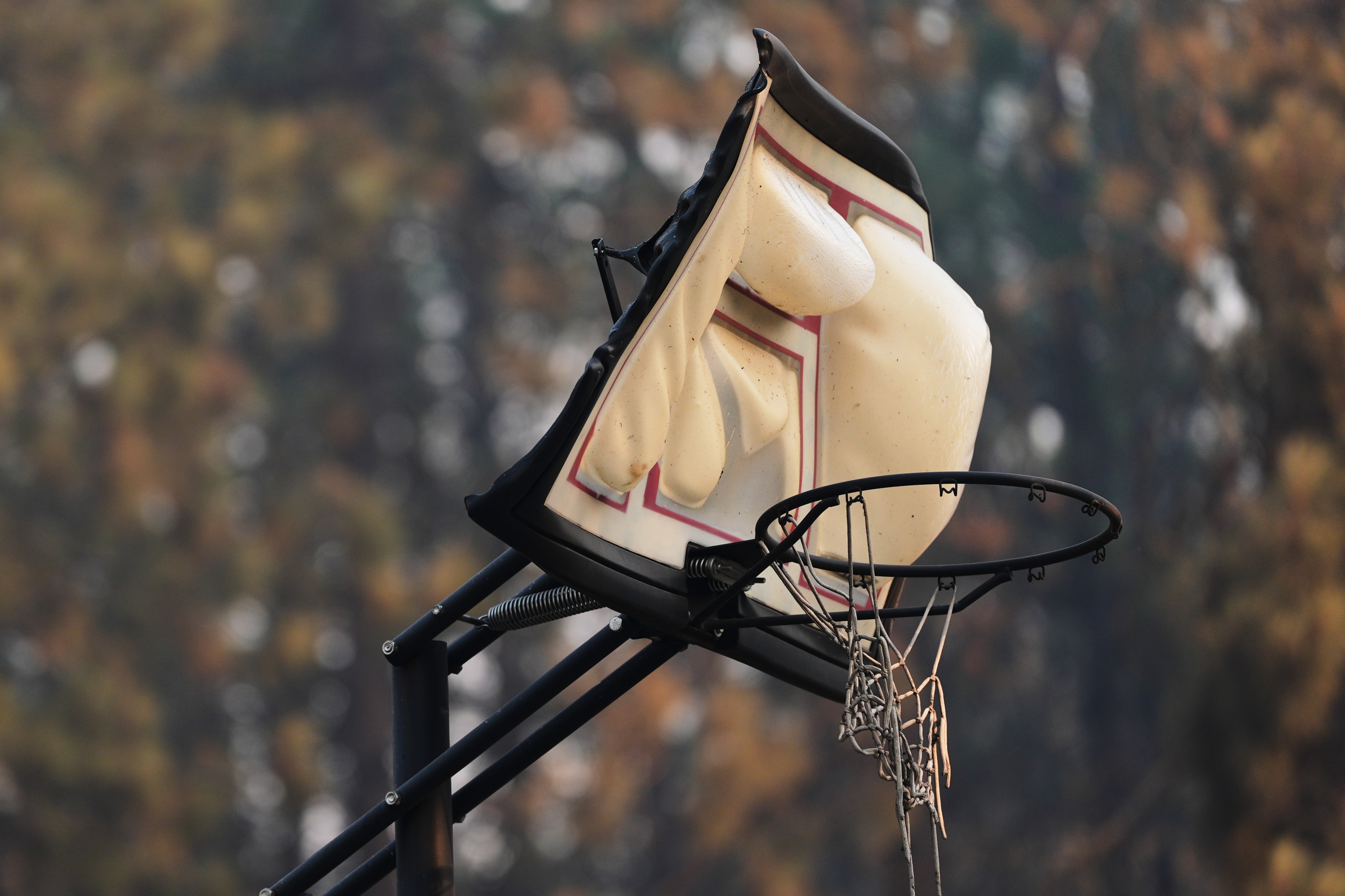 A melted backboard stands in a neighborhood after a wildfire passed through.