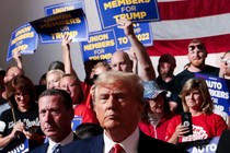 Trump in front of autoworkers holding signs.