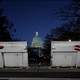 At night, the U.S. Capitol is visible in the background, with large white barricades with the word "Stop" in the foreground.