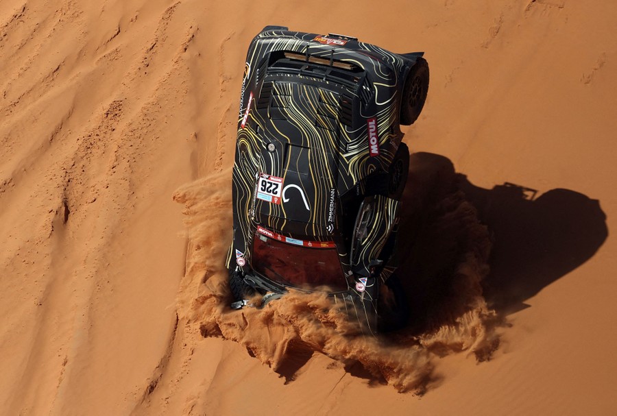A rally car crashes nose-first into a sand dune during a race.