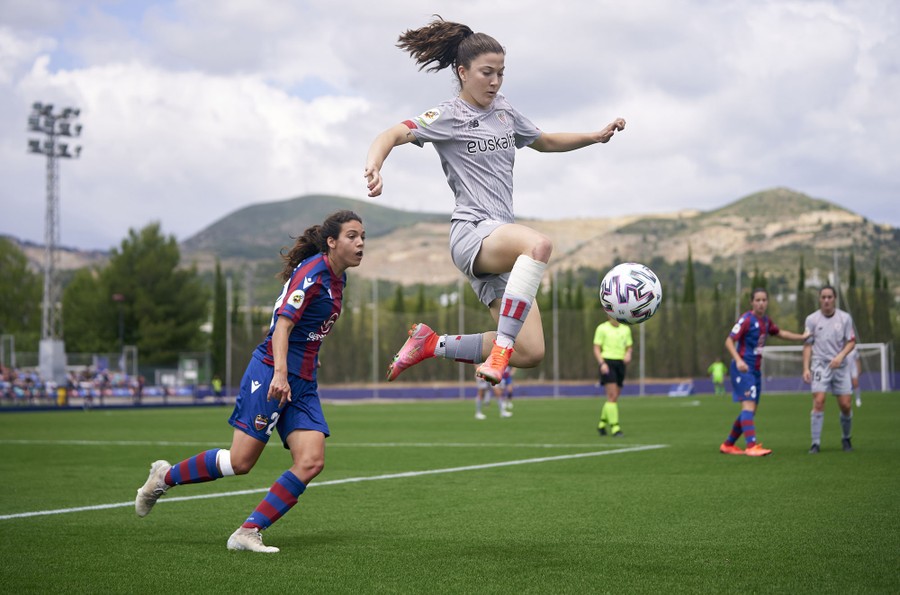 A person jumps while controlling a ball during a soccer match.